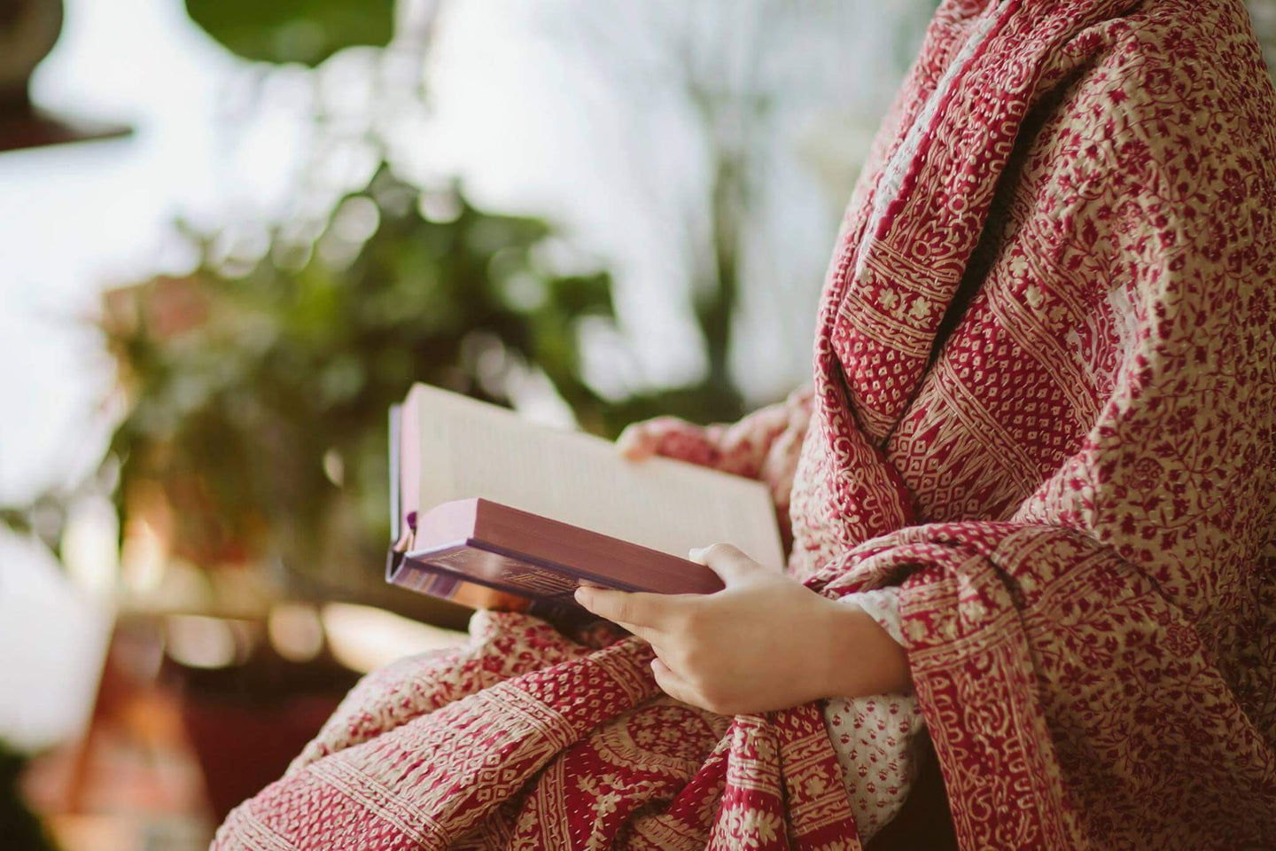 woman reading book wrapped in sari blanket